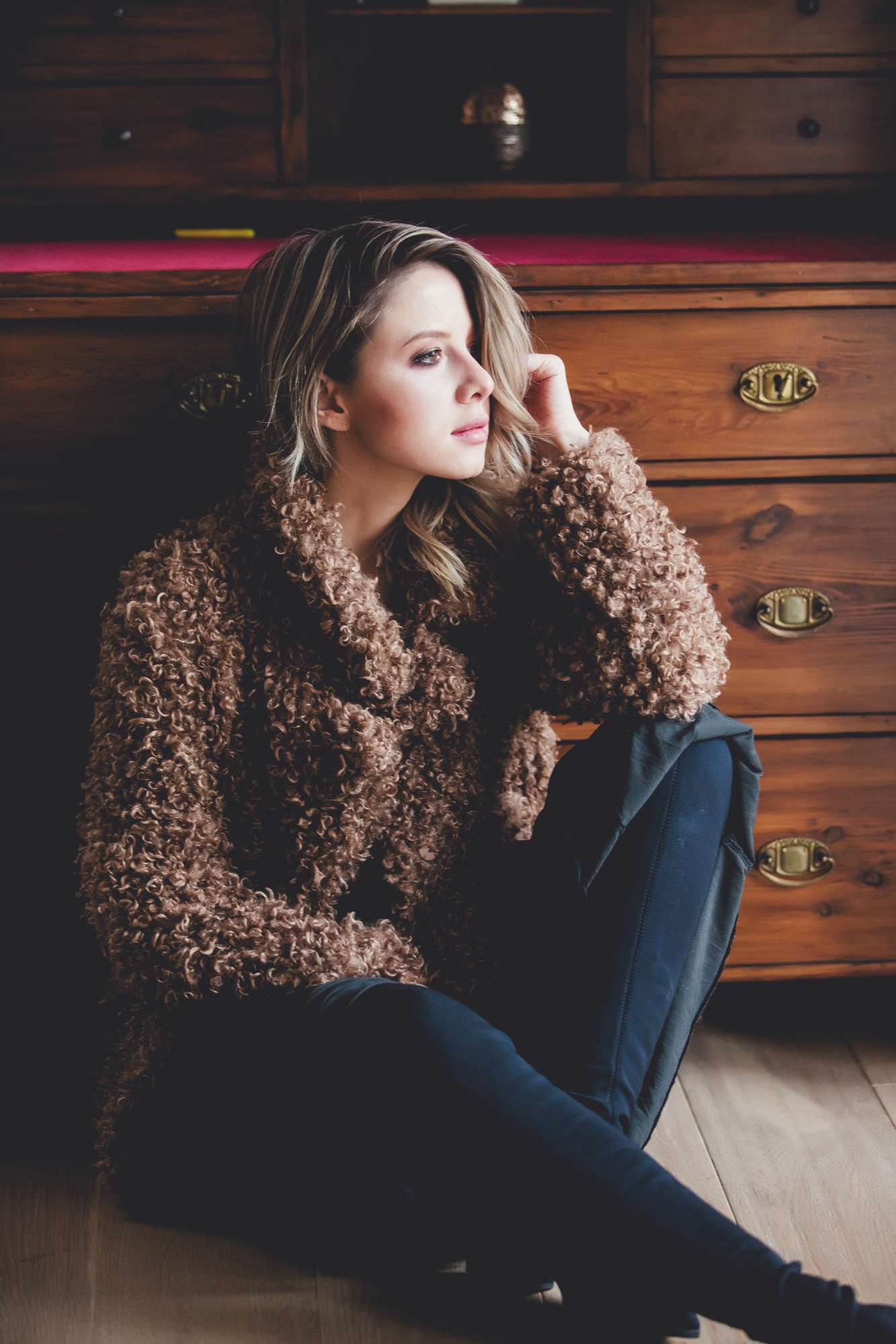 girl with makeup in coat sitting at floor at home